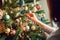 person, decorating christmas tree with variety of ornaments, including handmade ones