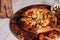 Person delicately slicing pizza on a cutting board with a sharp knife