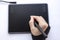 A person draws on a graphics tablet. A hand in a drawing glove holds a touch pen. A wireless graphic tablet for the designer