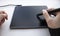 A person draws on a graphics tablet. A hand in a drawing glove holds a touch pen. A wireless graphic tablet for the designer