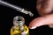 Person dripping drop of extract oil on finger with eyedropper