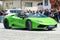 a person driving a green Lamborghini  sports car down a street with people watching