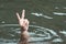 A person drowns in a river or lake and shows a symbol of victory and freedom. Male hand in the water with hand raised up. Winner