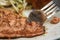 Person eating grilled salmon with pasta and salad on a plate