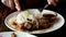 Person eats appetizing fried meat sprinkled with onions on a white plate,