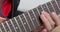 Person fingers the frets along the neck and presses strings, playing chords on an electric guitar, close up. Rehearsal