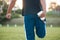 Person, fitness and stretching leg on grass getting ready for sports training, workout or outdoor exercise. Rear view of