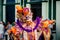 Person in flamboyant costume poses for photo by city street at dominican carnival