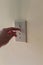 Person flipping light switch on a wall