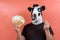 Person with funny latex cow mask holding bills and making the gesture of earning money