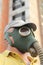 Person in gas mask closeup on destroyed building background.