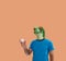 Person gesture with frog mask catching a professional baseball in hand as amateur on orange background