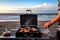 person, grilling juicy burger on portable grill, with view of the beach