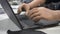 Person with hand bionic prostheses is typing on laptop at laboratory table.