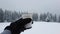 Person hand holding a cup of hot mulled wine or coffee outdoors on the top of the mountain in the winter day with snow falling. Wo