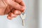 Person hand holding key to new home. Rent, mortgage loan, investment, real estate and own property