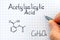 Person hand with pen writing chemical formula of Acetylsalicylic Acid.