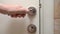 Person hand pressing metal handle closes door in bathroom