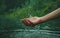 person hand splashing water drops at lake or river, human palm splash aqua