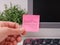 A Person hand sticking a pink paper note with the reminder Deadline on it on to a monitor at an office workplace