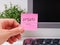 Person hand sticking a pink paper notes with the reminder Update on to a monitor at an office workplace