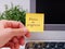 Person hand sticking a yellow paper notes with the reminder Focus on Progress on it on to a monitor at an office workplace