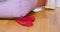 Person hand takes lost dirty red sock hidden near couch