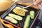 Person hand with tweezers frying organic zucchini on grill iron pan. Close-up grilled sliced vegetables cooking process for vegan