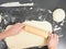 Person handling a dough with a wooden rolling pin