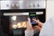 Person Hands With Mobile Phone In Front Of Oven
