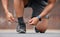 Person hands, sports and tie shoes for running workout, training and action performance on ground outdoor. Closeup of