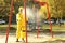 Person in hazmat suit with disinfectant sprayer cleaning children`s playground. Surface treatment during coronavirus pandemic