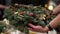 Person holding beautiful and colourful hand made Christmas wreath, green spruce branches decorated with pine cones and other