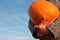 A person holding big orange pumpkin on the bright blue sky background. Female hands in gray sweater with huge pumpking.