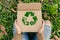 Person Holding Cardboard Box With Green Recycle Sign. Generative AI