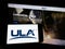 Person holding cellphone with logo of American space company United Launch Alliance (ULA) on screen in front of webpage.