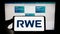 Person holding cellphone with logo of German energy company RWE AG on screen in front of business webpage.