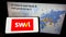 Person holding cellphone with logo of mass transit company SWVL Technologies Inc. on screen in front of business webpage.