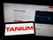 Person holding cellphone with logo of US cybersecurity company Tanium Inc. on screen in front of business webpage.