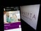 Person holding cellphone with webpage of US company Sarepta Therapeutics Inc. on screen in front of logo.