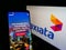 Person holding cellphone with website of Malaysian carrier Axiata Group Berhad on screen in front of business logo.