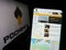 Person holding cellphone with website of Russian oil and gas company PJSC Rosneft on screen in front of logo.