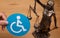 Person holding the disability sign with the sculpture of Themis the Greek goddess of justice