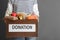 Person holding donation box with food on gray, closeup