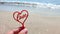 Person holding fingers hand stick shape red heart word Love background sand