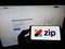 Person holding mobile phone with logo of Australian fintech company Zip Co Limited on screen in front of business web page.