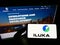 Person holding mobile phone with logo of Australian mining company Iluka Resources Limited on screen in front of web page.