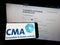 Person holding mobile phone with logo of British Competition and Markets Authority (CMA) on screen in front of web page.