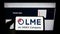 Person holding mobile phone with logo of British exchange London Metal Exchange (LME) on screen in front of web page.