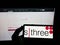 Person holding mobile phone with logo of British recruitment company SThree plc on screen in front of business web page.